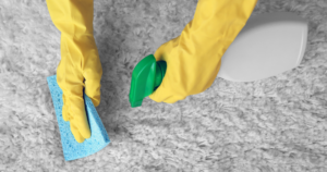 Cleaning grey carpet with cleaner and sponge