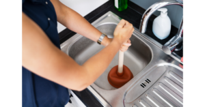 Person holding plunger over blocked drain sink